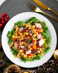 Salpicon de pulpo. Octopus salad with chickpeas, arugula and vegetables. Top view table with christmas decorations.