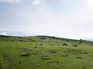 views of hills and green grass against the background of a bright blue sky that is slightly cloudy