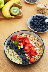 Healthy breakfast avocado smoothie bowl with fresh fruits and chia seeds on wooden table