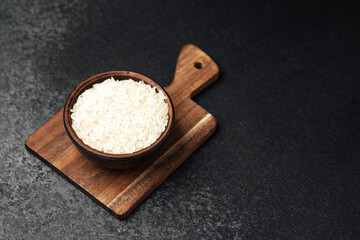 White rice in a bowl on a wooden cutting board in a kitchen setting