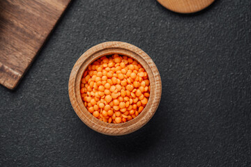 Bright orange lentils in a wooden bowl on a dark background