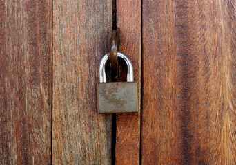Vintage locked padlock with chain at brown wooden door background, Closeup
