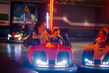 Mother and daughter enjoying bumper cars at amusement park