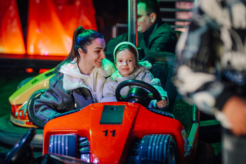 Mother and daughter enjoying bumper cars at amusement park