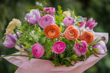Spring bouquet. Beautiful multi colored fresh flower arrangement. Birthday bouquet made of tulips and ranunculus photographed outdoors.