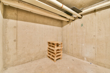 An empty space featuring concrete walls and a wooden pallet positioned in the center, showcasing industrial elements and minimalist design.