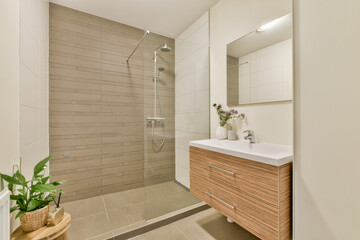 A contemporary bathroom featuring elegant tiles, a modern shower, and natural decor elements like...