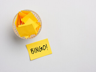 To play bingo game. Lottery ticket with the word bingo near a glass bowl full of rolled paper sheets.