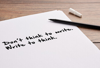 The motivational message don't think to write write to think, handwritten on a white sheet of paper.