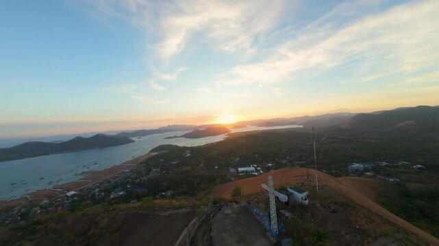 Sunset aerial view from Mount Tapyas over Coron town and bay with communications towers dry hillside islands and glowing evening sky in Palawan