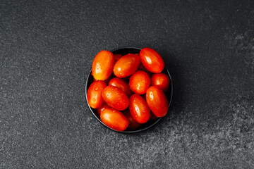 Fresh cherry tomatoes arranged on a black plate ready for cooking