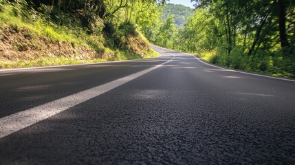 Fototapeta premium Winding mountain road through lush forest on a sunny day. Possible use travel, adventure, nature
