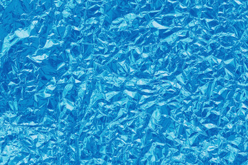 Shiny blue foil texture background, pattern of cyan wrapping paper with crumpled and wavy.