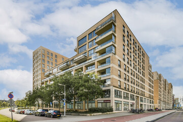 This image showcases a contemporary apartment building featuring balconies, large windows, and...