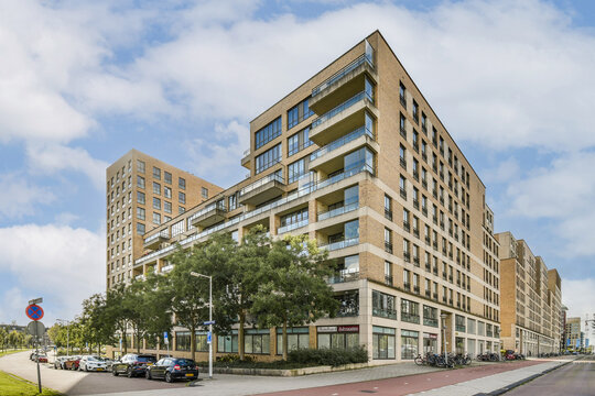 This image showcases a contemporary apartment building featuring balconies, large windows, and modern architectural design, set against a clear blue sky.
