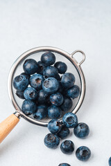Fresh blueberries in a sieve on a light background during a kitchen setting