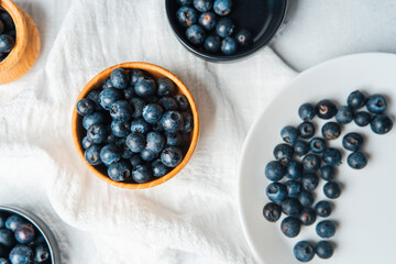Fresh blueberries arranged in bowls and plates on a white tablecloth