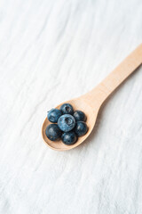 Fresh blueberries in a wooden spoon on a light background
