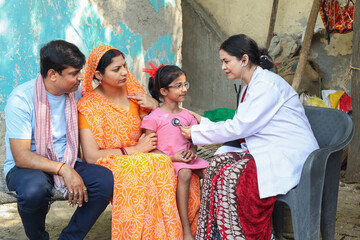 Indian female doctor check heart beat of little girl child sitting with her parents. Rural parents...