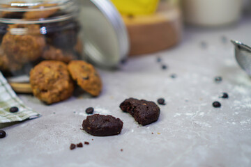 chocolate cookies that split in half, surrounded by chocolate chips, with jars filled with cookies behind it 