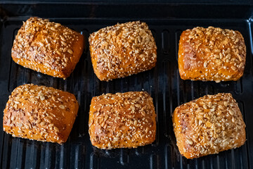 Freshly baked rolls with sunflower seeds emerging from the oven capturing the warmth of a home kitchen in golden hues and earthy aromas