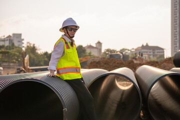 Engineer worker operations construction plans large black drainage pipe installing underground infrastructure heavy machinery importance of careful planning and teamwork in construction project.