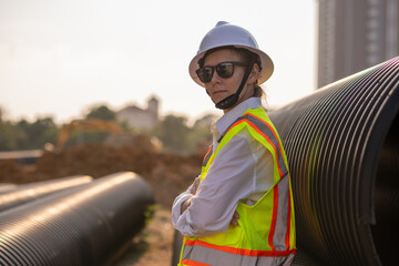 Engineer worker operations construction plans large black drainage pipe installing underground...
