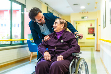 Doctor comforting elderly woman in wheelchair at nursing home