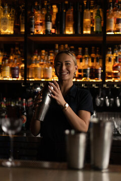 Young woman bartender makes a cocktail