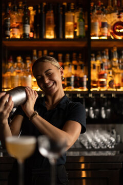 Smiling woman bartender preparing cocktail at bar counter