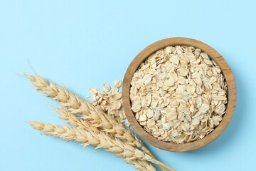 Composition with oatmeal flakes on blue background. Cooking breakfast