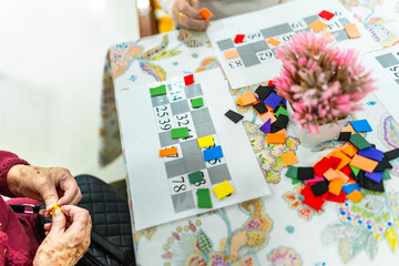 Senior woman playing bingo in nursing home, enjoying leisure activity