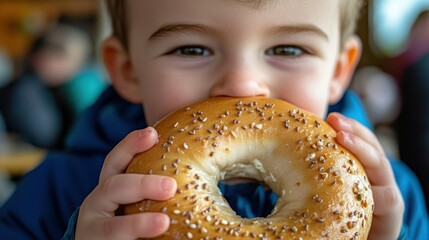 Naklejka premium A young boy smiles while eating a seeded bagel