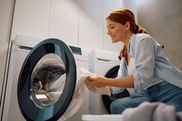 Happy woman doing laundry at home.