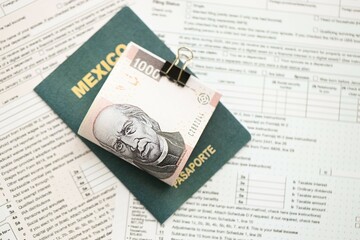 Mexican pesos money bills in big amount lies on table with passport and tax forms close up