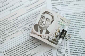 North Korean won money bills in big amount lies on table with tax forms close up