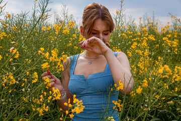 Young woman sneezing in field of yellow flowers