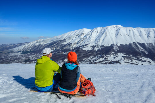 Two people taking a break while backcountry skiing in the Appennines, Italy