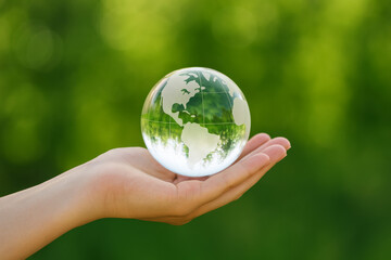 Embracing the Earth: A hand tenderly cradles a glass globe, the continents subtly reflected within, symbolizing care for the planet.