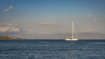 Obraz premium A sailboat glides gracefully across calm waters, reflecting sunlight from the blue sky, offering a serene escape into natures beauty and tranquility, Komodo archipelago, Indonesia