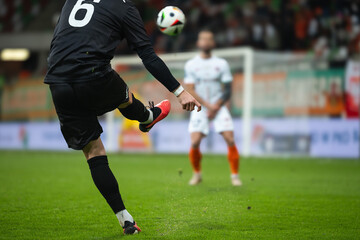 Soccer player kicks the ball during football match. Opponent player in the wall.