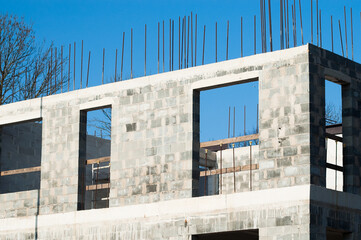 Fototapeta premium unfinished construction of an apartment building made of gray blocks, blue sky in the background