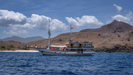 A luxury yacht anchored by a beautiful beach, surrounded by mountains and crystal clear waters, offers the perfect setting for adventure and relaxation, Komodo, Indonesia