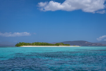 Imagine a serene tropical island with sandy beach, lush greenery, clear turquoise waters, and a bright blue sky, ideal for relaxation and exploring natural beauty, Komodo, Indonesia
