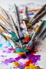 Obraz premium Assorted paintbrushes covered in various vibrant colors arranged on a textured surface