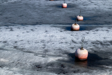 mooring buoys in harbor with melting ice