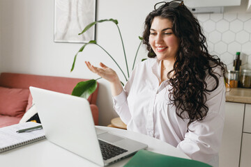 Side view of young caucasian female tutor having group video chat, explaining topic or new subject,...