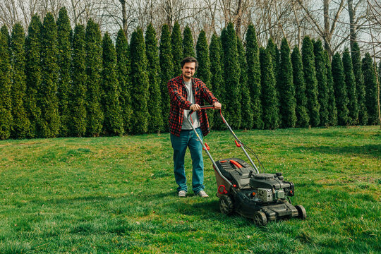 Man taking a break from lawn mowing in a suburban backyard during spring