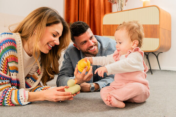Fototapeta premium Joyful family playing together with toys, engaging their adorable baby in delightful activities for cognitive and emotional development in a warm and loving environment