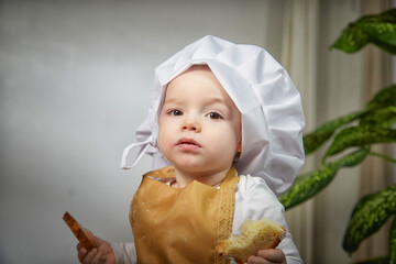 Young boy in a chef's hat poses thoughtfully in a cozy studio setting during a playful photo shoot